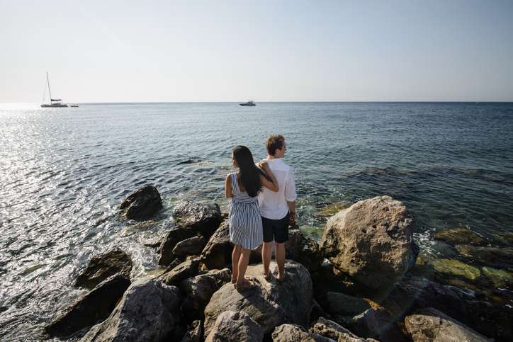 Où aller pour un séjour à la Saint-Valentin ? Couple sur un rocher, fixant l'horizon et face à la mer