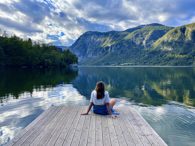le-slow-tourisme. Femme assise devant un lac et des montagnes en europe