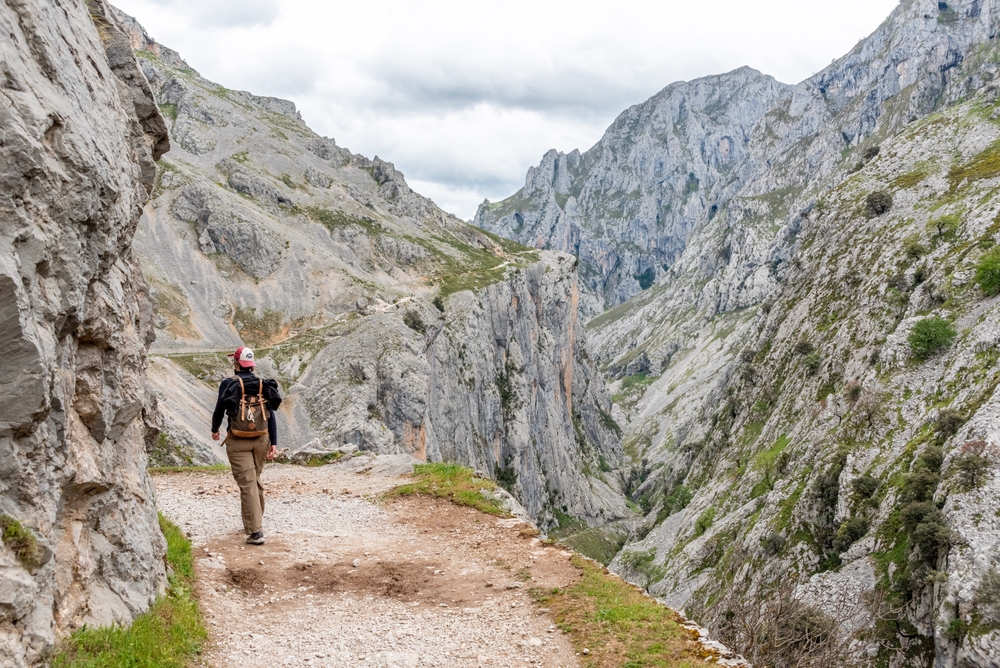 Where to go in Europe in June shutterstock 2525730767 cimagodens une touriste faisant de la randonnee dans les gorges pittoresques de cares dans les montagnes des picos de europa asturies dans le nord de lespagne