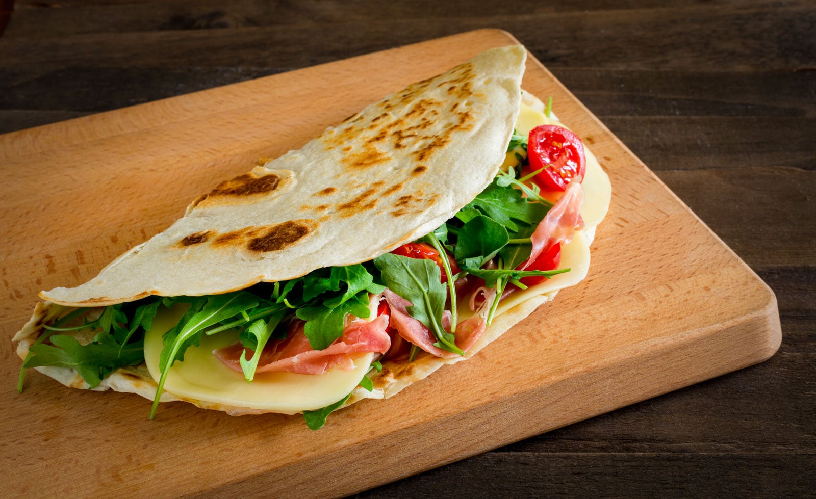 Italie du Nord Est shutterstock 1420643573 ©vincenzo de bernardo romagna piadina fourree de fromage de jambon de tomates et de fusee sur une planche a couper