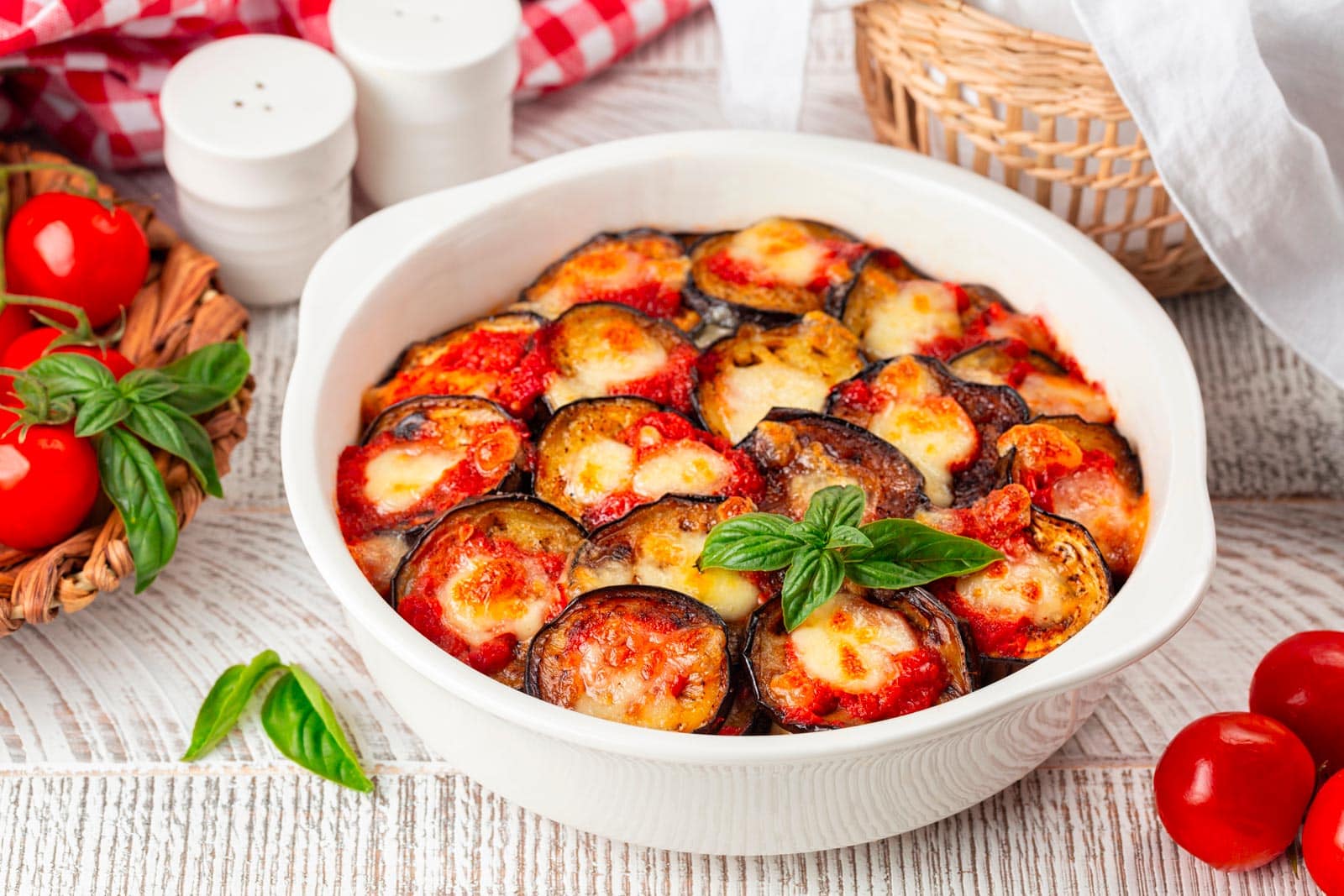 shutterstock 2179536487 ©olgabombologna italian dinner with homemade baked eggplant parmigiana di melanzane made with mozzarella tomato and basil leaves