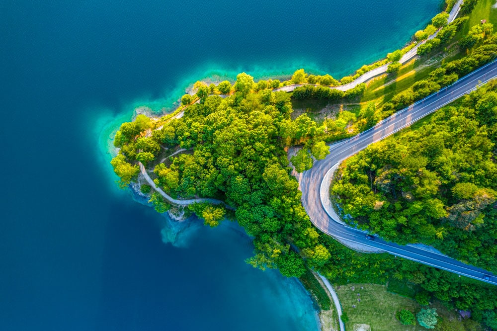 Italie du Nord Est shutterstock 2460293221 cfunk design vue aerienne sur le lac de ledro avec leau turquoise et la route des vents paysage estival anime dans le nord de litalie route panoramique du lac de ledro