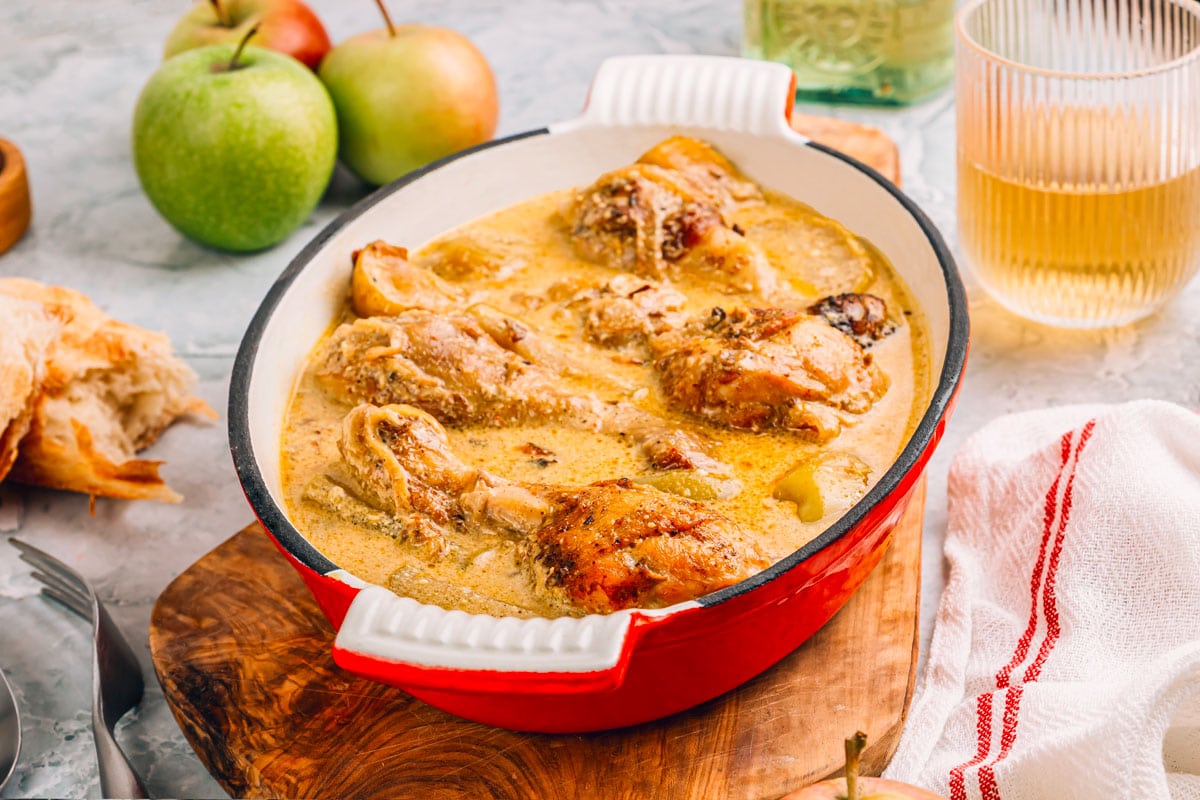Région Normandie shutterstock 2393687359 ©julia mikhaylova poulet de normandie servi dans moule en fonte recouvert demail pommes verre de cidre sur fond gris marbre. cuisine francaise. lidee de recette dautomne